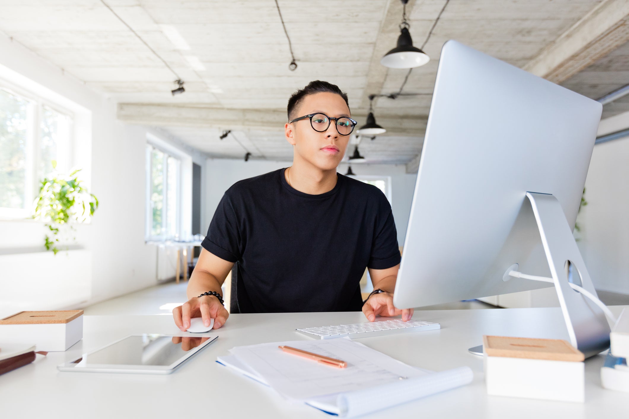 Person sitting at a desk with a computer and tablet in an office setting making money online building an e-commerce business